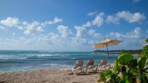 a group of chairs and an umbrella on a beach at Las Villas Akumal in Akumal