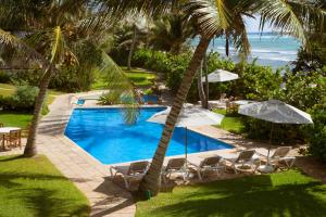 a pool with chairs and umbrellas next to the ocean at Las Villas Akumal in Akumal