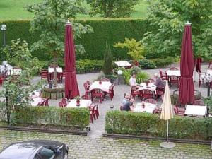 a group of people sitting at tables with red umbrellas at Hotel Bayerischer Hof Rehlings in Weißensberg