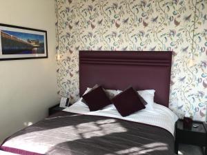 a bedroom with a bed with a headboard and a wall at Queenswood Hotel in Weston-super-Mare