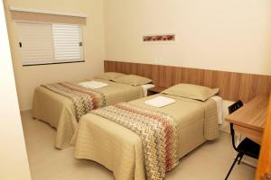 a hotel room with three beds and a desk at Siena Hotel in Pederneiras