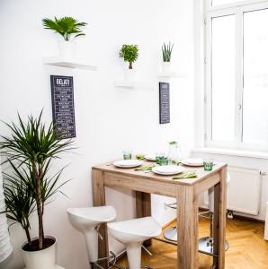 einen Esstisch mit weißen Stühlen und Pflanzen in der Unterkunft Vienna Lights Apartments - Karmarschgasse in Wien
