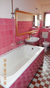 een roze badkamer met een bad en een wastafel bij Pension Behnisch in Strehla