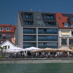 ein Restaurant mit Tischen und Sonnenschirmen vor einem Gebäude in der Unterkunft Apartments im s'Wirthaus in Friedrichshafen