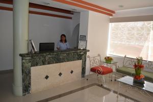 une femme debout à un comptoir dans une pièce avec un ordinateur portable dans l'établissement Hotel del Parque, à Ciudad del Carmen