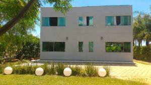 a white building with green windows in the grass at Casa no Lago de Furnas in Pontevila