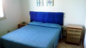 1 dormitorio con cama azul y mesita de noche en Appartamento Santangelo en Porto Palo
