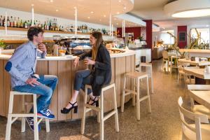a man and woman sitting at a bar in a restaurant at Hotel Eurorest in Conegliano