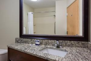 een badkamer met een wastafel en een spiegel bij AmericInn by Wyndham Osage in Osage