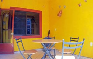 a table and chairs in a room with a yellow wall at Posada Familiar El Dorado in Xilitla