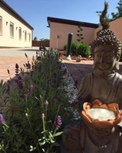 una estatua sosteniendo un bol de fruta en un jardín en Levendula Vendégház, en Győr