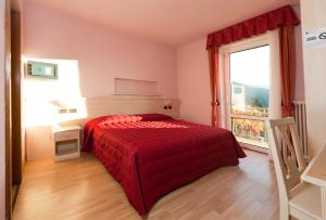 a bedroom with a red bed and a window at Life Hotels Rosalpina in Folgaria