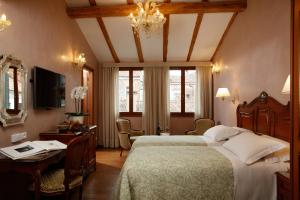 um quarto com uma cama, uma secretária e uma televisão em Hotel Bisanzio em Veneza