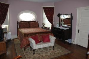 Victorian Charm Inn في Towanda: غرفة نوم بسرير وكرسي ومرآة