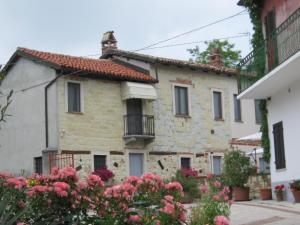 a stone house with a balcony and pink flowers at Albergotto Natalina in Grazzano Badoglio