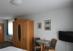 a bedroom with a cabinet and a table and a tv at Gästehaus Kleine Kalmit in Landau in der Pfalz