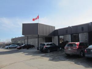 a building with cars parked in a parking lot with a canadian flag at Nor Villa Hotel in Winnipeg
