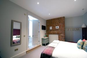 een slaapkamer met een bed en een bakstenen muur bij The Coach House in Potton