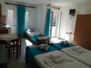 three beds in a room with blue curtains and a kitchen at Olympic Star in Hersonissos +75 photos