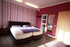 a bedroom with a bed with purple walls and a mirror at VacApps Apartments in Leipzig