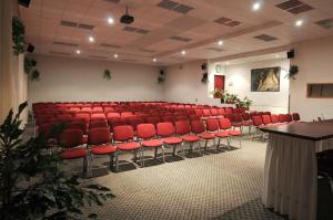 an empty auditorium with red chairs in a room at Hotel SOREA ĽUBOVŇA in Stará Ľubovňa