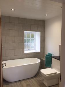 a bathroom with a tub and a toilet and a window at Smithy House in Forfar