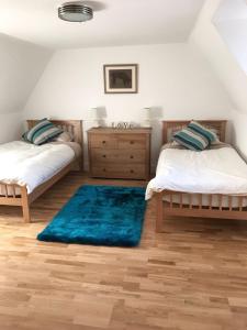 a bedroom with two beds and a blue rug at Smithy House in Forfar