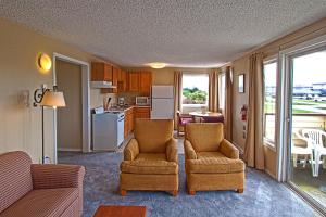 a living room with two chairs and a kitchen at Ocean Shores Inn & Suites in Ocean Shores