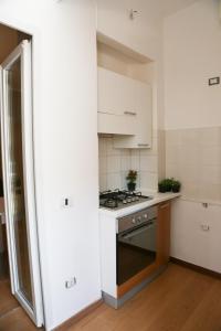 La cuisine est équipée de placards blancs et d'un four avec plaques de cuisson. dans l'établissement Casa Bea, à Quartu SantʼElena