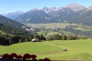 un pasto verde con un granero en las montañas en Alpengasthaus Gleinserhof, en Schönberg im Stubaital