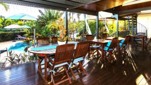 eine Terrasse mit einem Tisch, Stühlen und einem Pool in der Unterkunft Reflections Broome in Broome