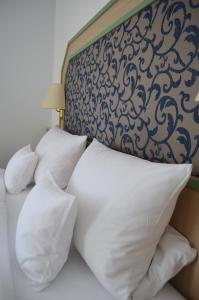 1 cama con almohadas blancas y cabecero en Apart' Hotel, en Kehl am Rhein