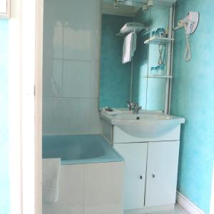 ein Bad mit einem Waschbecken und einem Spiegel in der Unterkunft Hotel Au Petit Béarn in Salies-de-Béarn