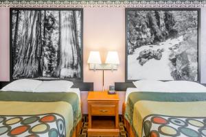 two beds in a hotel room with posters on the wall at Super 8 by Wyndham Grants Pass in Grants Pass
