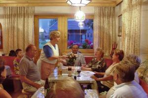 een vrouw die praat met een groep mensen die rond een tafel zitten bij Haus Schweigl in Obsteig