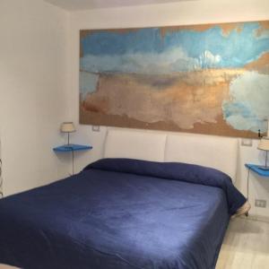 a bedroom with a blue bed and a painting on the wall at My suite Sorrento in Sorrento