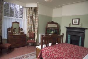 1 dormitorio con cama, escritorio y espejo en Dylan Thomas House en Swansea