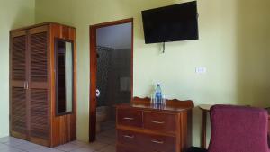 a living room with a tv and a dresser at Anchorage Beach Resort Caye Caulker in Caye Caulker