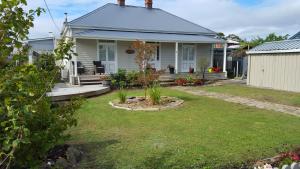 a white house with a porch and a yard at Windsor Cottage in Kingston Beach