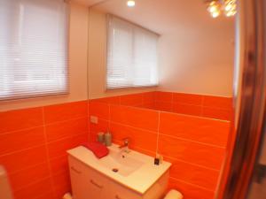 Windsor Cottage في Kingston Beach: حمام به جدران من البلاط البرتقالي وحوض