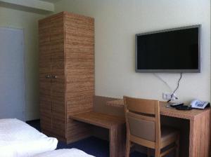 Schlafzimmer mit einem Schreibtisch und einem TV an der Wand in der Unterkunft Gästehaus Café Ruff in Happurg