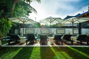 a group of chairs and umbrellas in a yard at Villa Dewata II in Seminyak