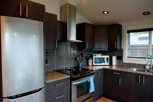 a kitchen with wooden cabinets and a white refrigerator at Fish Tales Cottage in Port Renfrew