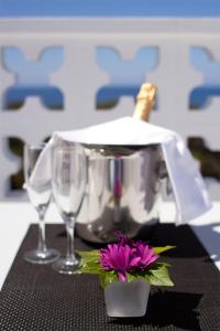 カラ・ヴァデラにあるHotel Villageのワイングラス2杯と紫の花のテーブル