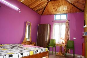 een slaapkamer met paarse muren en groene stoelen bij Eagle Nest Home Stay in Guwahati