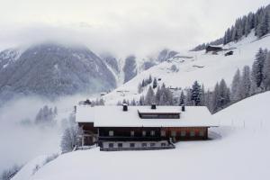 un edificio cubierto de nieve en una montaña nevada en Goserhof, en Innervillgraten