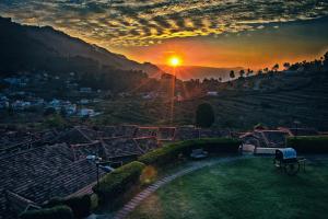 a view of a city with a sunset in the background at Green Pastures - A Hill Country Resort in Kodaikānāl