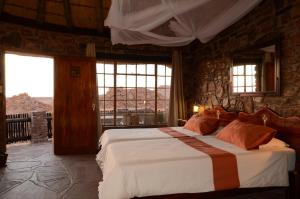 ein Schlafzimmer mit einem großen Bett in einem Zimmer mit Fenstern in der Unterkunft Gondwana Canyon Lodge in Kanebis