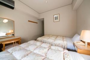 a bedroom with two beds and a desk and a mirror at Sansuikan Kawayu Matsuya in Hongu