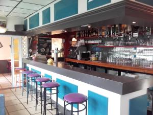 a bar with purple stools in a restaurant at Hotel de la Plage in Quinéville